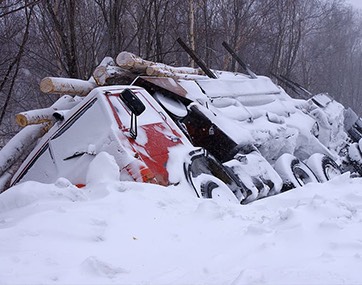 truck turned on its side on road shoulder in winter